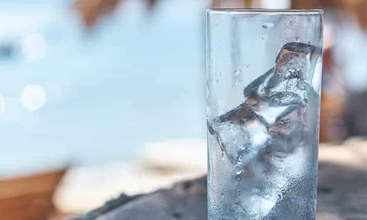 copo com gelo em cima de mesa em praia.