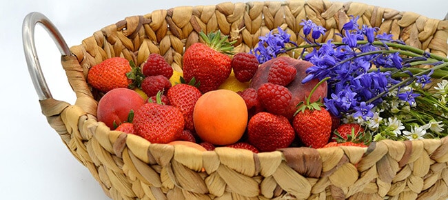 frutas organizadas em uma cesta com flores