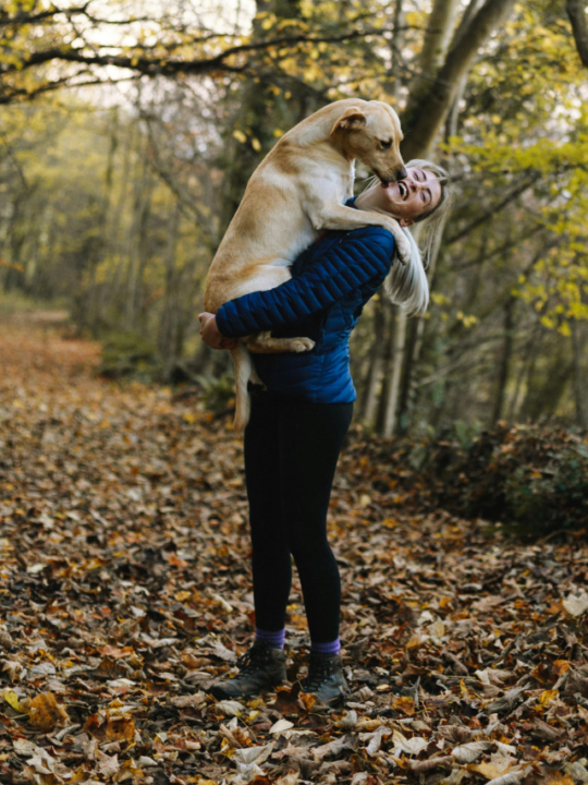 Tutora segurando labrador bege no colo.