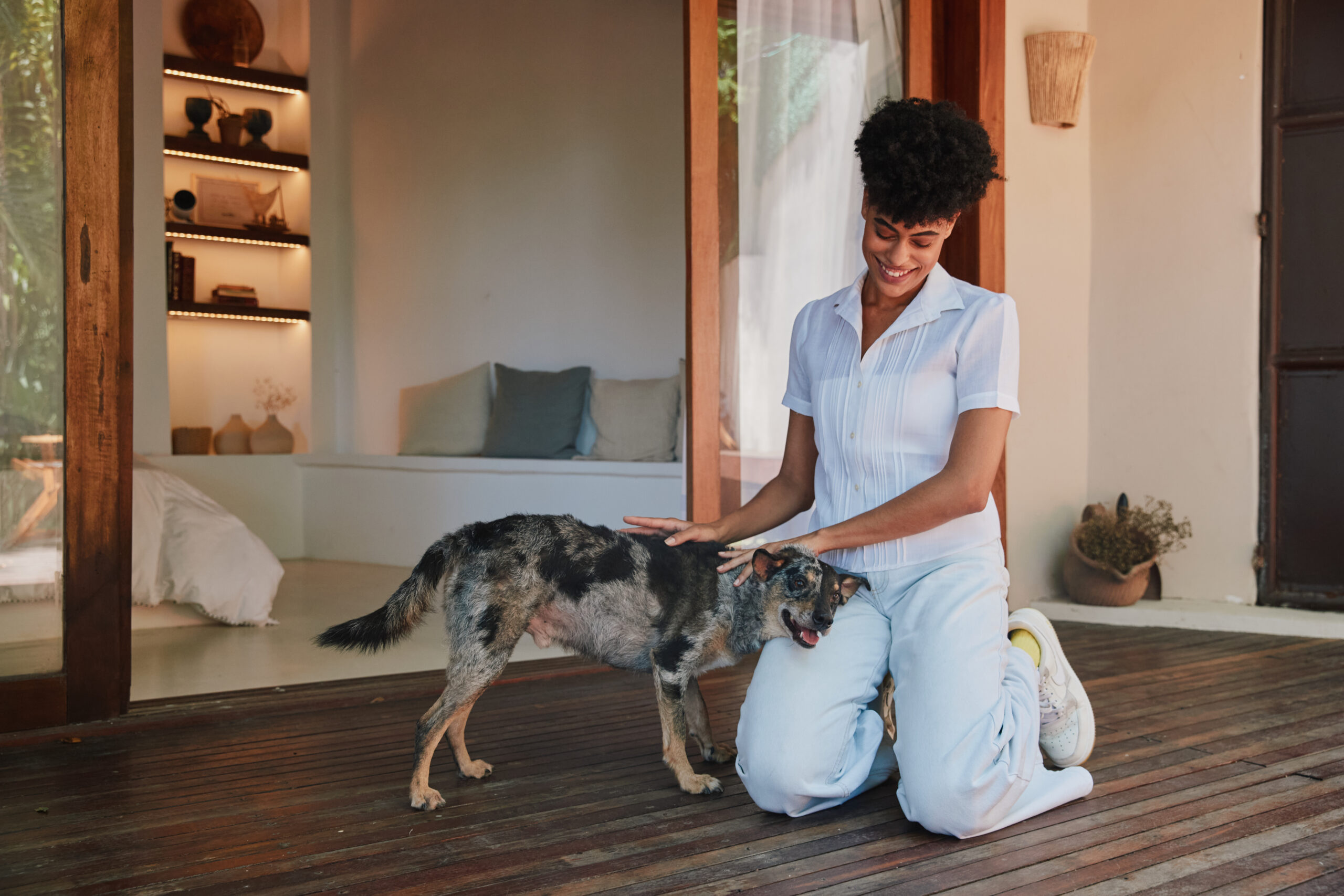 Responsável ajoelhada, fazendo carinho em cachorro.