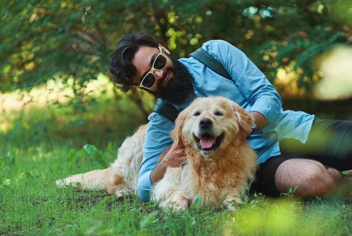Cachorro e homem deitados na grama.