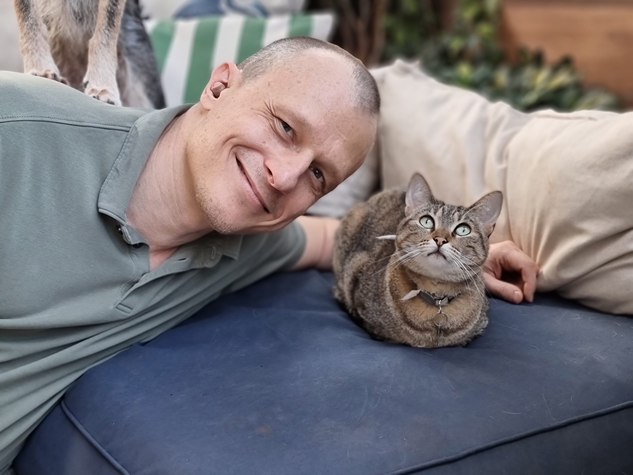 Como os pets impactam a nossa saúde emocional? 1 Dr. Pet sorrindo ao lato de gato, que está deitado em sofá.