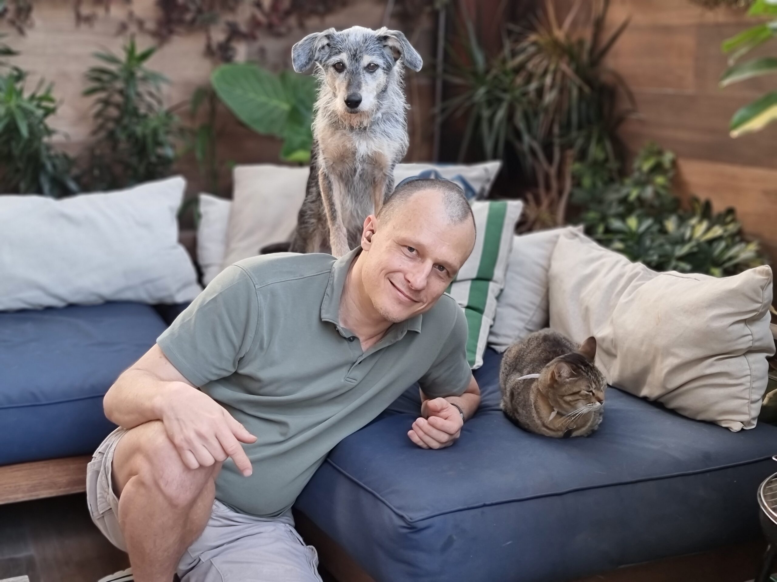 Dr. Pet com cachorro nas costas e um gato ao lado, no sofá.