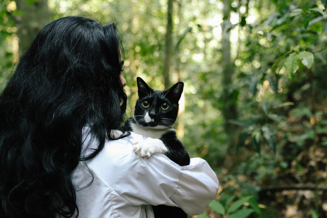 Tutora com gato preto no colo.