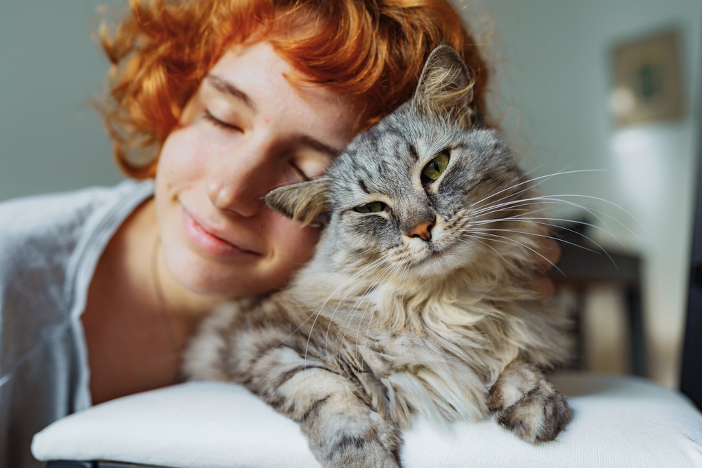 Tutora com a cabeça apoiada no gato.